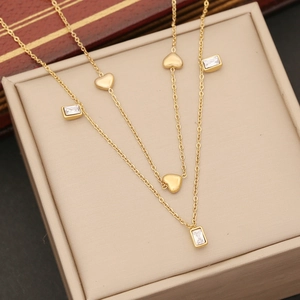 Elegant gold double-layered heart necklace with cubic zirconia gems on jewelry box