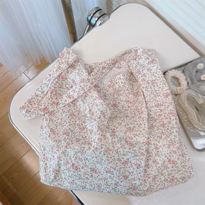 Vista plana de un bolso de algodón con flores rosas y azules sobre un escritorio blanco