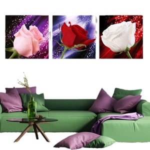 Three-piece set of red pink and white rose wall art canvas paintings over a green sofa
