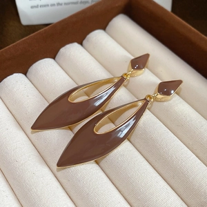 Macro shot of elegant coffee brown enamel hollow teardrop earrings with gold metal accents