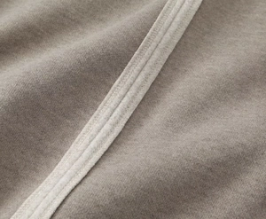 Détail macro du tissu du manteau en laine café-gris et bordures cousues blanches