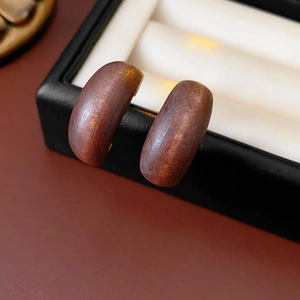 Detailed close-up of dark brown wooden C-shaped earrings showing natural grain texture