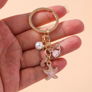 Golden keychain with pink enamel seahorse whale starfish pendants and a faux pearl charm