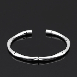 Macro view of a retro silver bamboo joint open cuff bracelet on reflective surface