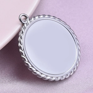 Macro detail of a silver round pendant with rope edge texture on a soft background