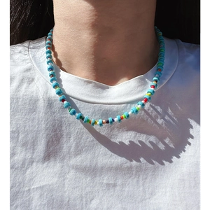 Rainbow beaded necklace with blue turquoise and pink crystal on white t-shirt