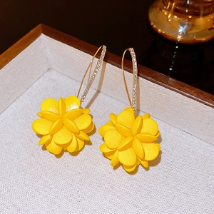 Close-up of yellow floral ball earrings with sparkling rhinestones on the curved ear hooks