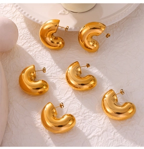 Detailed close-up of thick C-shaped gold-plated stud earrings with polished finish