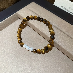 Close-up of vintage tiger eye beads and white pearls on a minimalist jewelry tray