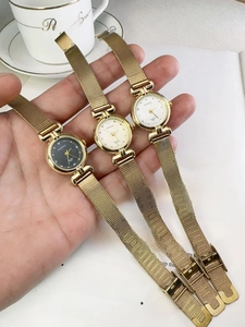 Three elegant vintage gold quartz watches with woven metal straps on a wrist