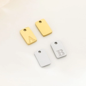 Detailed view of gold and silver rectangular metal pendant charms with letter engravings