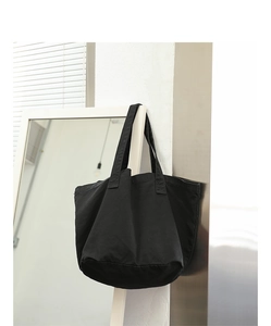 Minimalist black canvas tote bag hanging on a mirror in a clean, modern interior setting