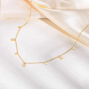 Elegant gold titanium necklace with geometric zircon charms on white stone and satin
