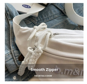 Detail view of smooth double zippers and woven rope pulls on a white canvas crossbody bag