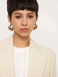 Close-up of 18K gold plated chunky C-shaped hoop earrings worn by a model in beige