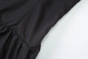 Close-up of black ruched fabric texture and stitching detail on a slim fit dress