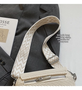 Detail view of the beige woven crossbody bag with vintage patterned wide shoulder strap