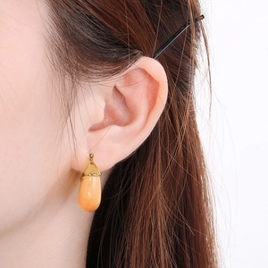 Detail of water drop jelly earrings in coral orange on a golden stainless steel post