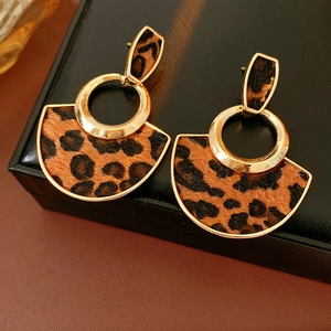 Macro shot of gold-plated fan-shaped earrings with brown leopard print texture
