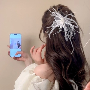Détail d'une pince à cheveux en plumes d'oie blanches et dentelle sur cheveux ondulés