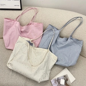 Detailed top view of three canvas tote bags in pink, blue, and white with silver star patterns