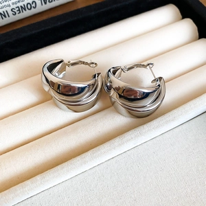 Close-up of silver double-layered C-shaped hoop earrings with a mirror-polished finish