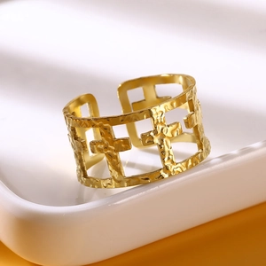 Detail of gold wide band ring with hammered texture and hollow cross pattern
