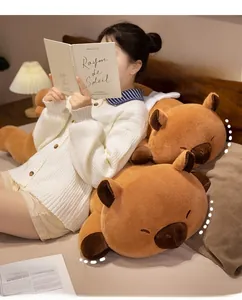 Cozy scene showing a long plush capybara body pillow used as a soft backrest for reading