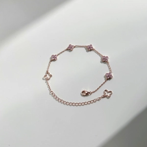 Detailed view of a rose gold clover tennis bracelet with pink zircon and butterfly charm