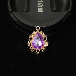 Vue macro d'un pendentif en cristal violet serti dans une base en dentelle dorée