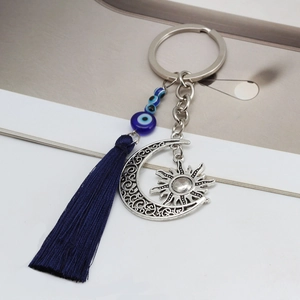 Detail showing vintage silver moon pendant and blue evil eye charms with silk tassel