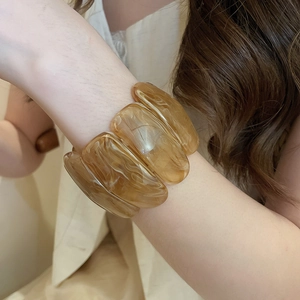 Detail view of amber acrylic bracelet showing marble texture and wide rectangular beads