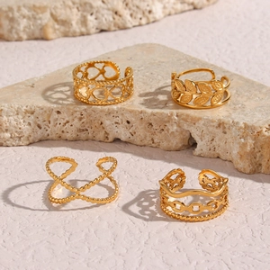 Detailed view of four gold-plated braided open rings with hollow heart and leaf designs
