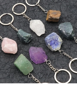 Macro shot of eight natural raw crystal gemstones on keychains over a dark background