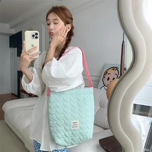 Detail of light green heart quilted shoulder bag with contrasting pink strap and fabric label
