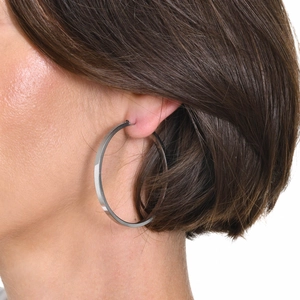 Close-up of polished silver hoop earring with flat surface on a model with short hair