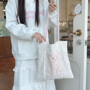 Close-up of white lace tote bag with floral embroidery and pink rope handles