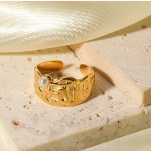 Detail of 18k gold lava texture ring with pearl on stone surface and silk background