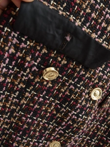 Close-up of pink tweed texture with metallic gold threads and a round gold button