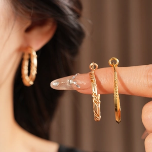 Detailed view of twisted gold hoop earrings and textured C-shape studs on model