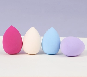 Primo piano di quattro morbide spugne per il trucco in rosa, bianco, blu e viola