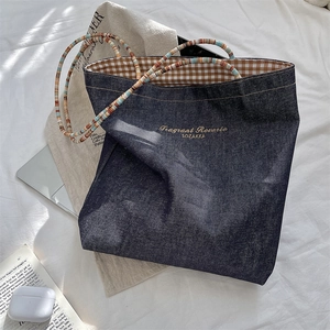 Detail view of retro denim tote bag with colorful beaded handles and brown plaid lining