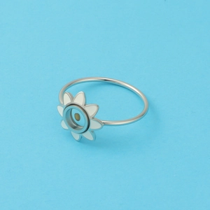 Detailed close-up of a silver sunflower ring with white enamel petals on blue background
