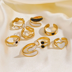 Minimalist gold star and heart enamel rings set on soft white silk fabric background