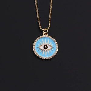 Macro detail of gold-plated evil eye necklace pendant with blue enamel and white crystals