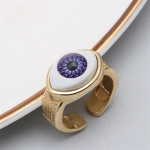 Close-up of golden copper evil eye open ring featuring a purple iris and hammered texture