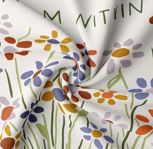 Close-up of soft white fabric with colorful floral prints and M WITHIN lettering detail