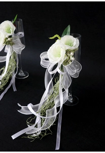 Detail of white wedding champagne glass flowers with faux roses, organza ribbons and pearls
