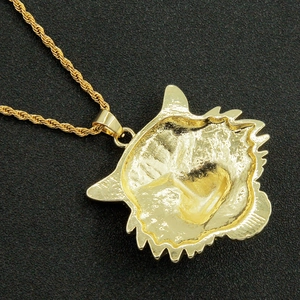 Detailed close-up of a bold gold lion head pendant with a twisted rope chain necklace