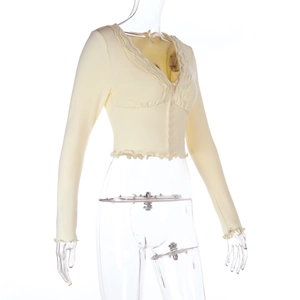 Detail of light yellow knit cardigan with ruffled edges and small round buttons